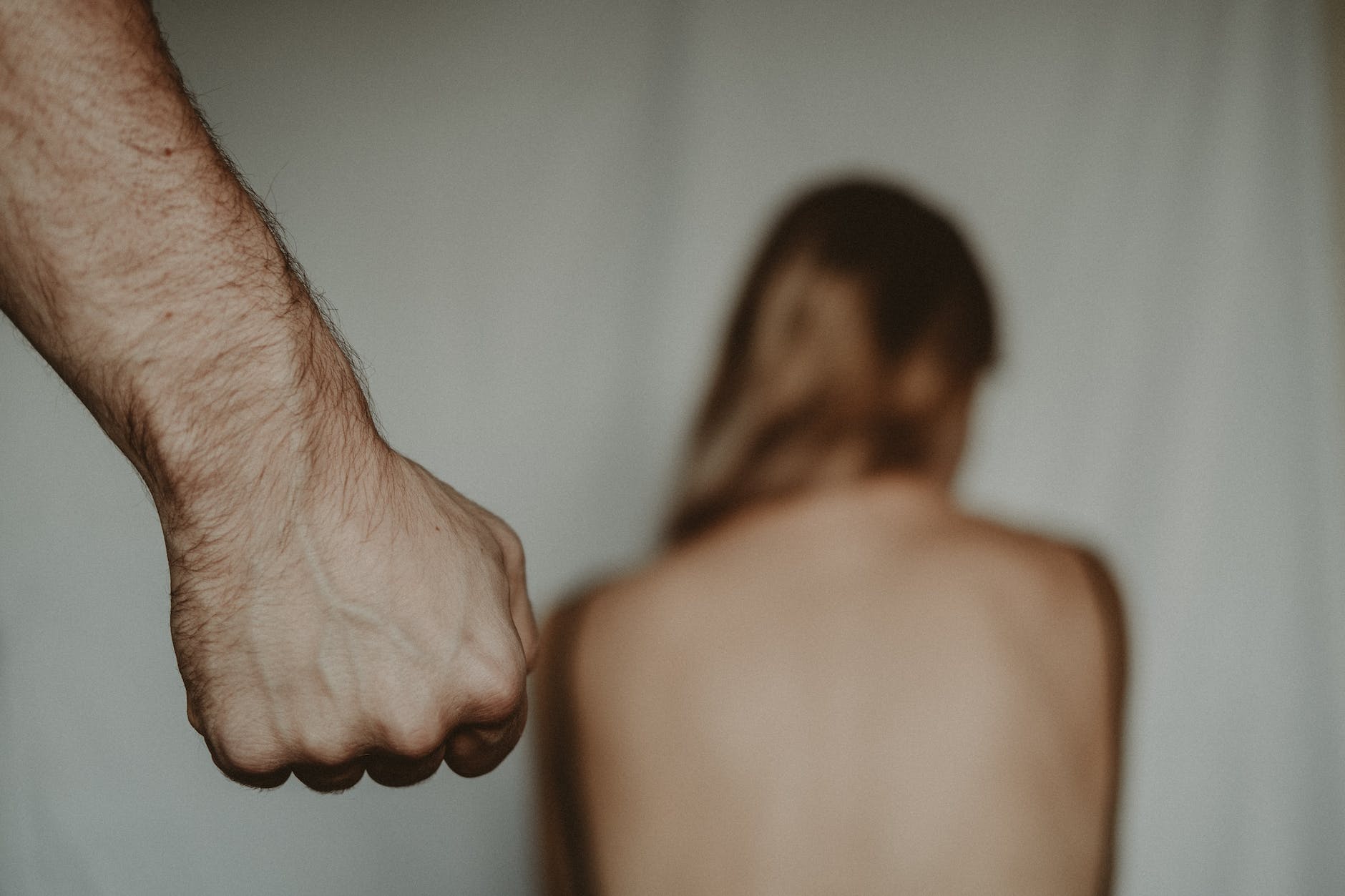 fist of crop man near helpless anonymous woman