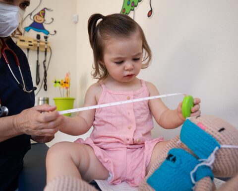 A pediatrician examines a toddler at a medical clinic