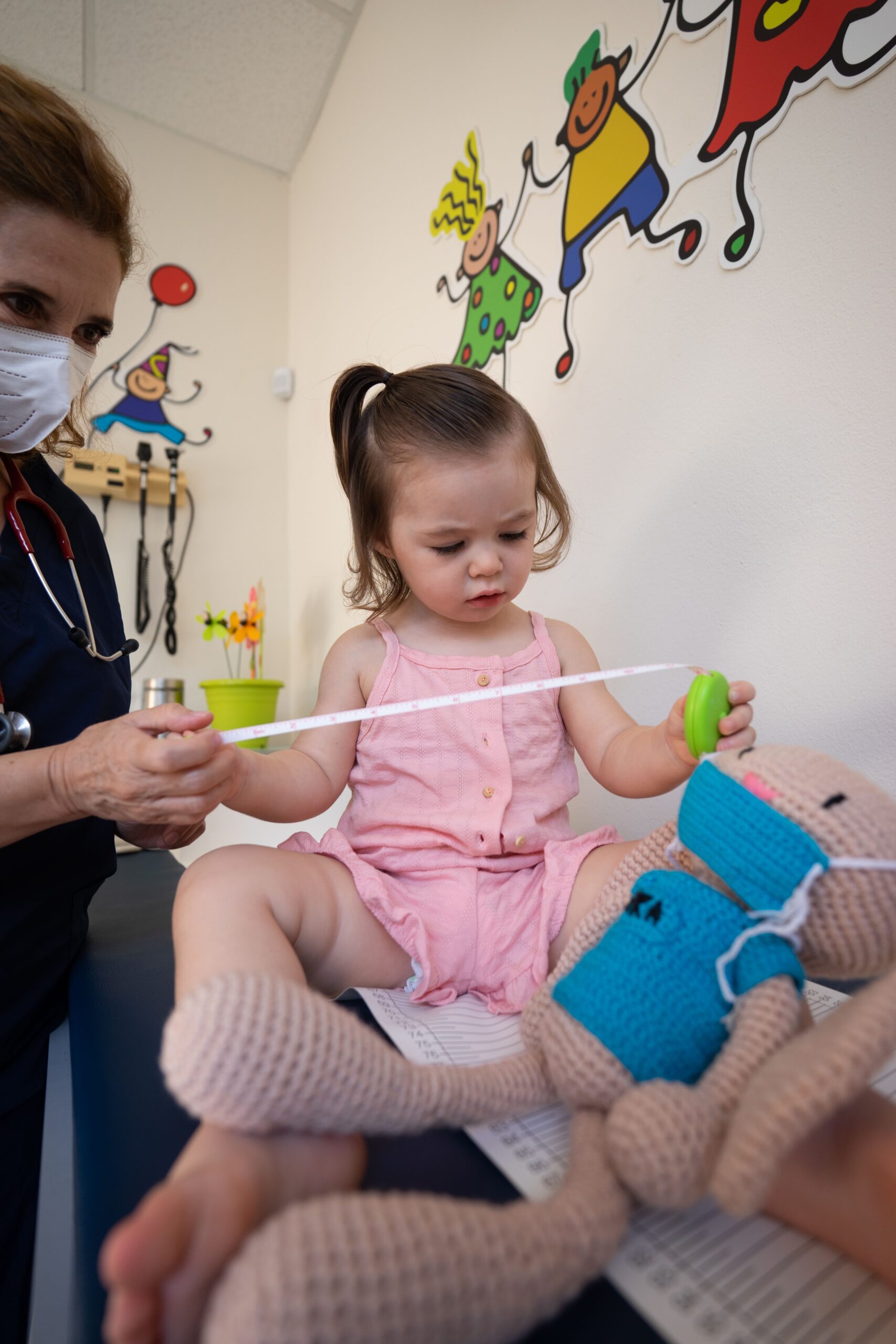 A pediatrician examines a toddler at a medical clinic