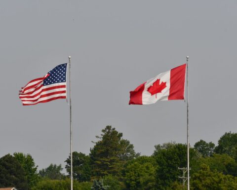 Flags of Canada and the United States flying side by side at the Canada–U.S. border
