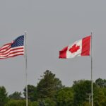 Drapeaux du Canada et des États-Unis flottant côte à côte, symbole de la frontière canado-américaine